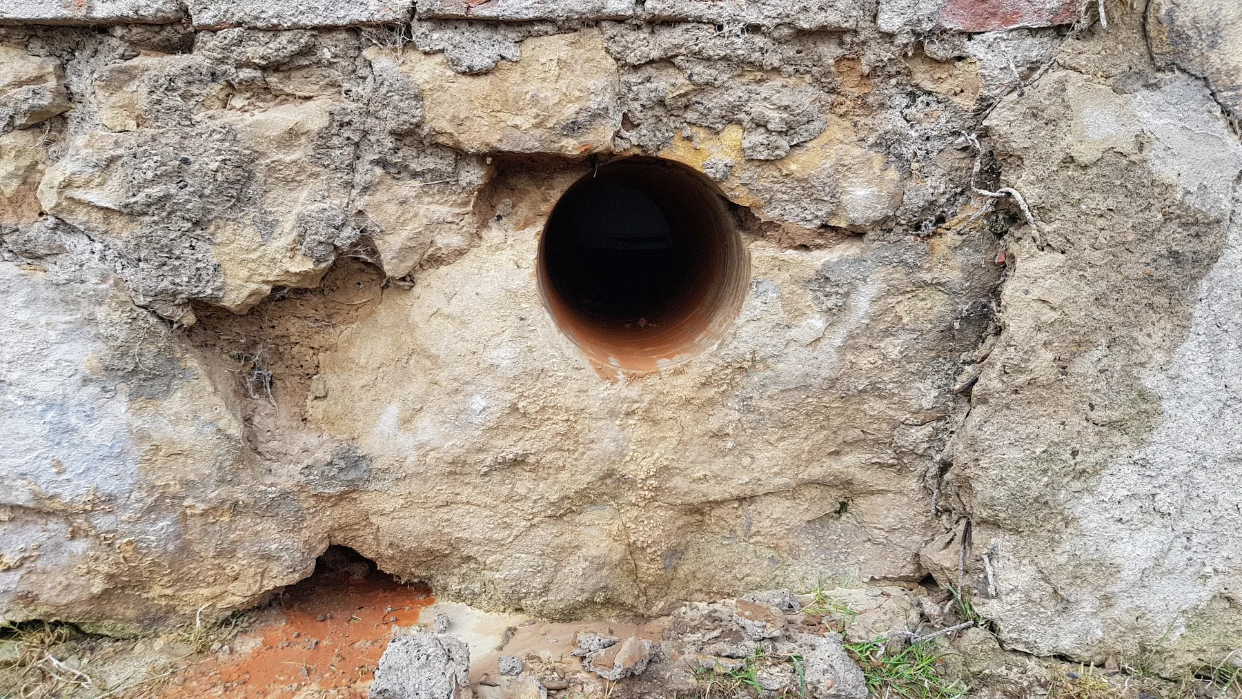 Kruhový otvor v nepravidelném kamenném zdivu.
