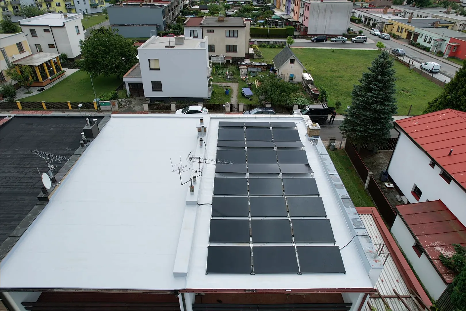 Letecký pohled na uspořádání fotovoltaických panelů na ploché střeše.