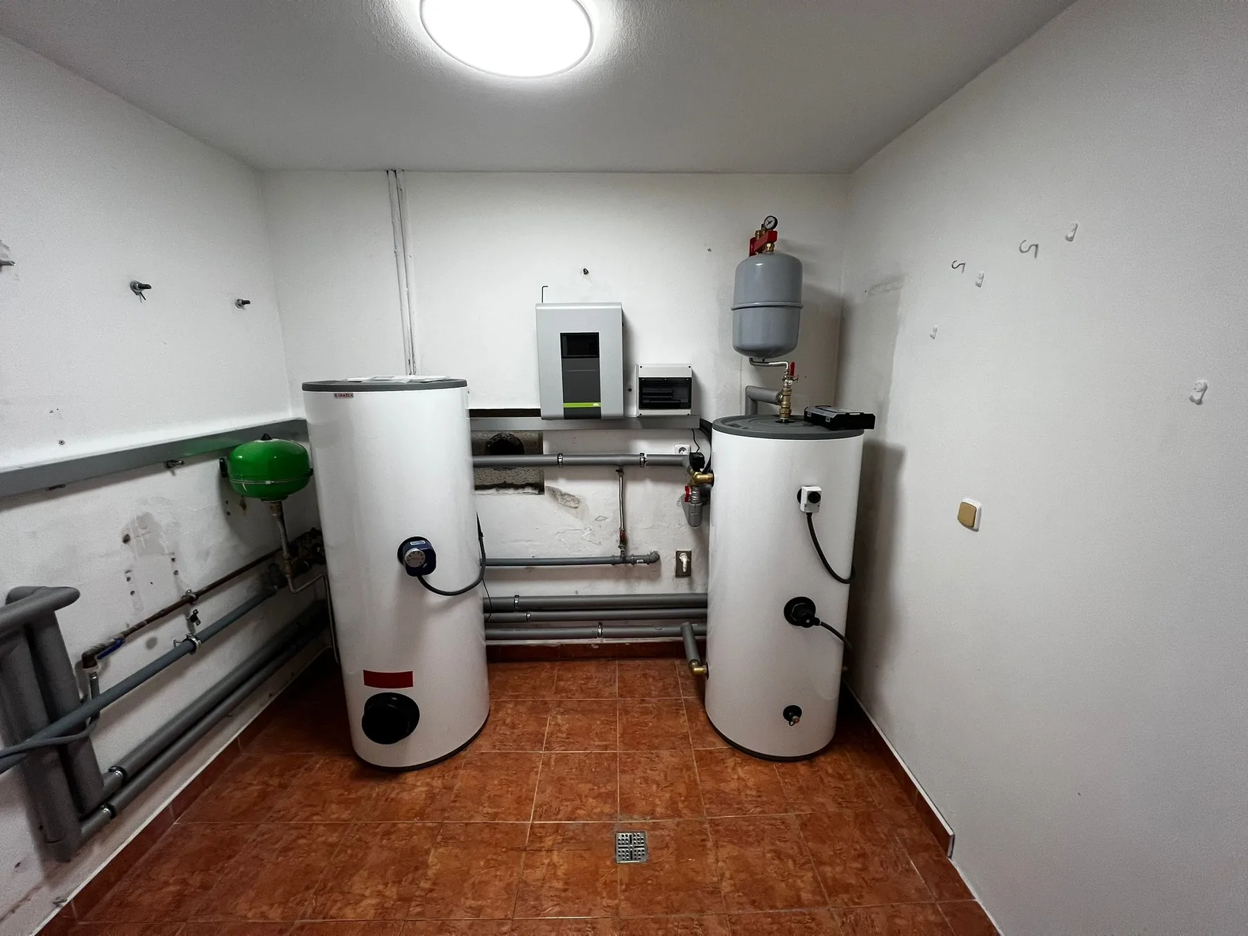Širší pohled na sestavu zásobníků, nástěnnou technologii a vedení rozvodů.