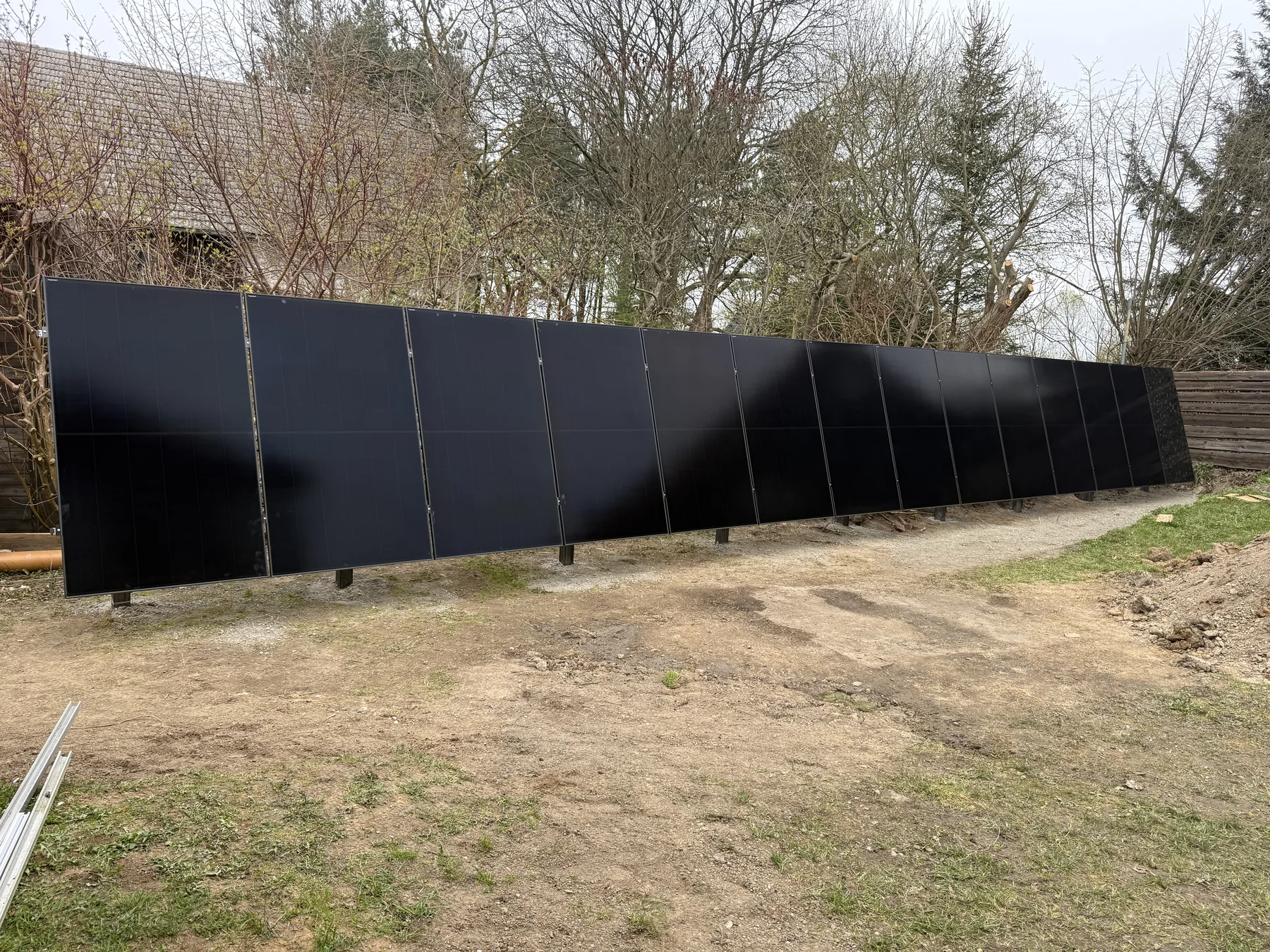 Řada fotovoltaických panelů osazená v terénu.