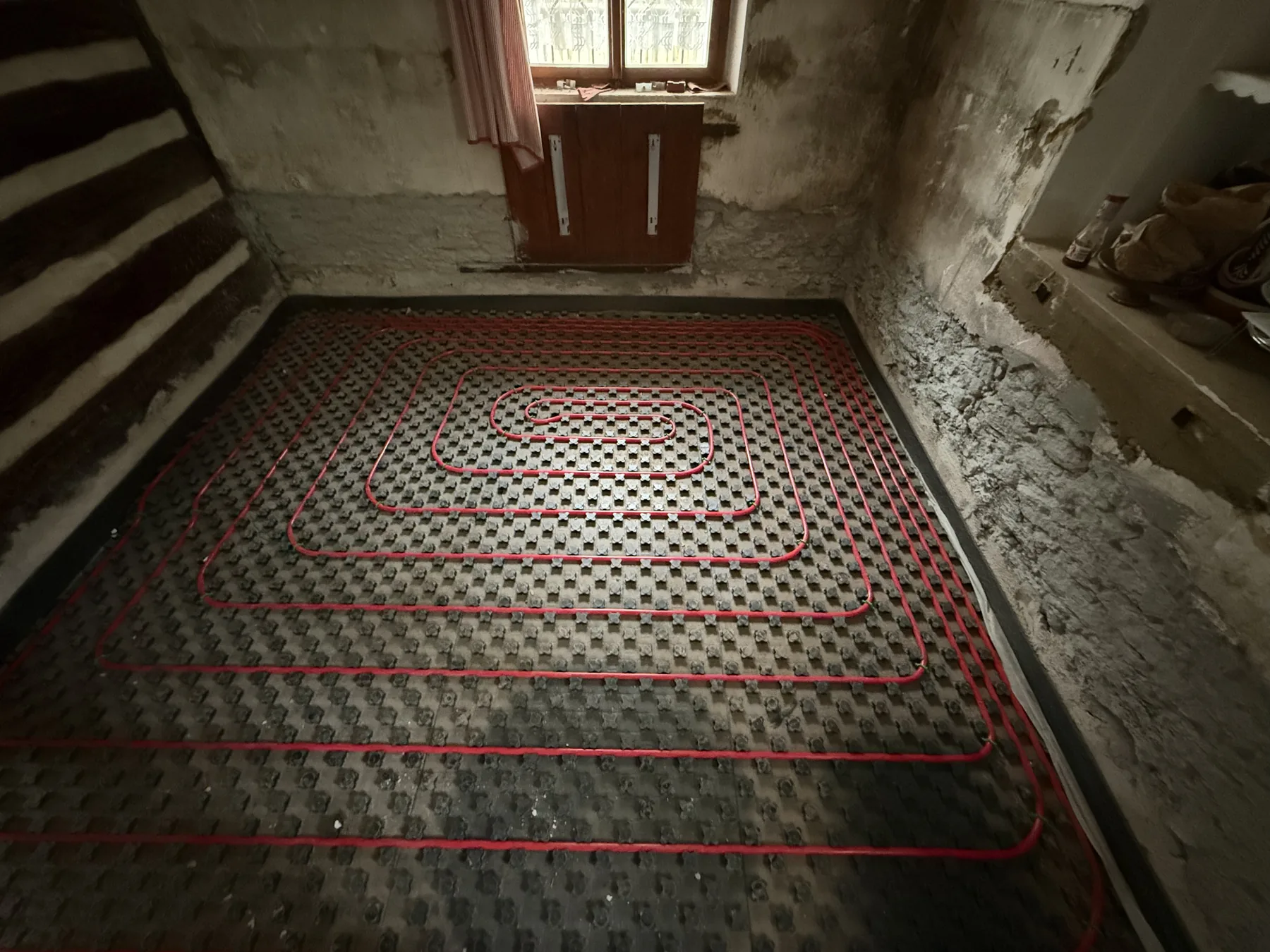 Rozložení topných smyček mezi stěnami malé místnosti před zalitím.