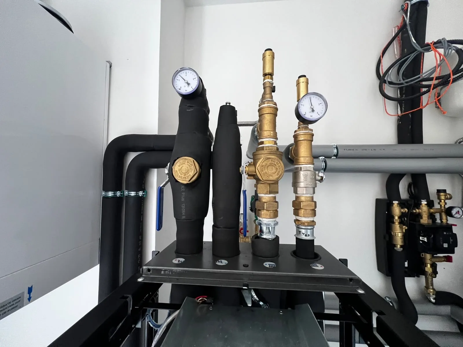 Detail ventilů, tlakoměrů a izolovaného potrubí nad technologií.